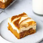 Carrot cake cheesecake bars topped with cream cheese frosting and walnuts